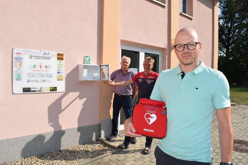 Der Defibrillator befindet sich an der Westseite der Turnhalle, direkt am Eingang. Für ein Pressefoto wurde das Gerät aus dem Kasten genommen.