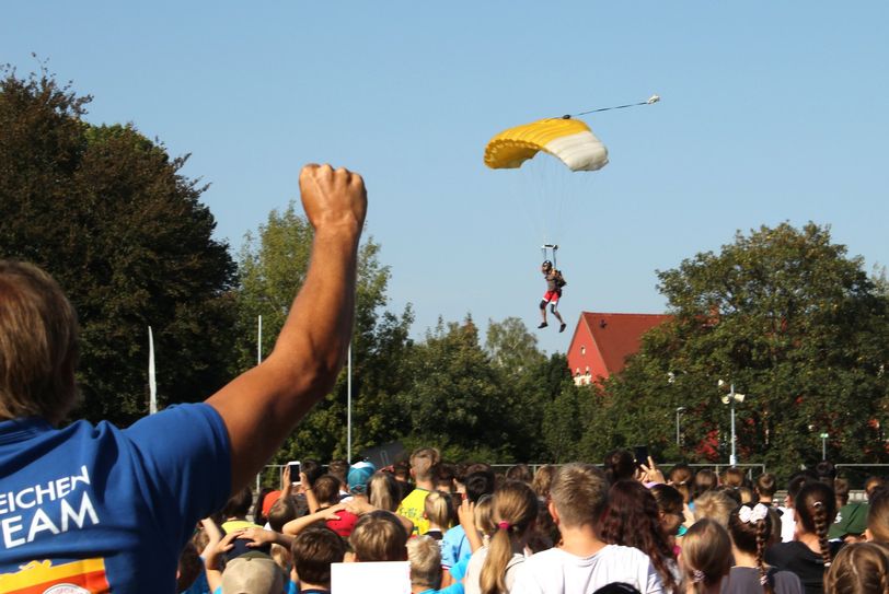 Einer der drei Fallschirmspringer landet zielgenau im Stadion.