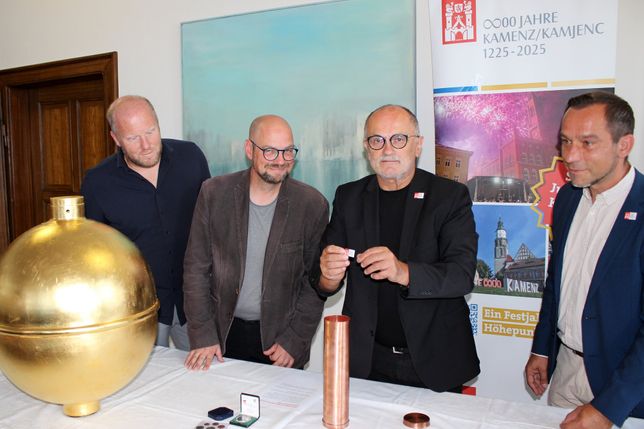 Im Beisein von Baudezernent Michael Preuß (l.), dem Stadtarchivar Thomas Binder (2.v.r.) und Projektkoordinator Maik Fabisch (r.) befüllt Oberbürgermeister Roland Dantz (2.v.l.) die Kartusche für die Turmkugel des Kamenzer Rathauses.