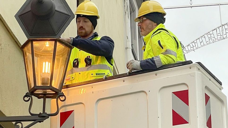 Mitarbeiter der Meißener Stadtwerke setzen die erste neue Leuchte in der Burgstraße ein.  Die Lichtfarben sind sehr ähnlich.