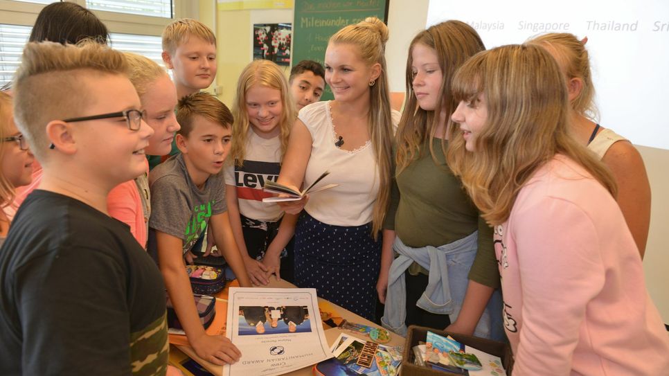 Melanie Reinecke (Mitte) ist jetzt als Lehrerin an der Grundschule am See in Senftenberg tätig. Im Foto zeigt sie den Schülerinnen und Schüler der Klasse 6a im Englischunterricht ihre Souvenirs von ihren Reisen rund um die Welt. Foto: Peter Aswendt