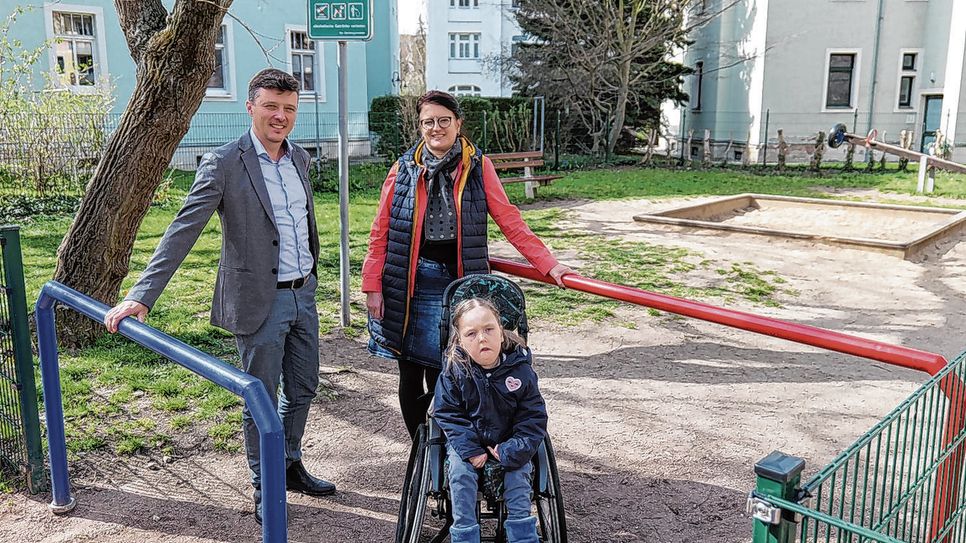 Bürgermeister Markus Renner (l.) und Kitaleiterin Carina Richter sind froh: Dank des erfolgreichen Projekts aus dem Bürgerhaushalt 2023 kann Ida (r.) nun den Spielplatz an der Bergstraße barrierefrei erreichen.