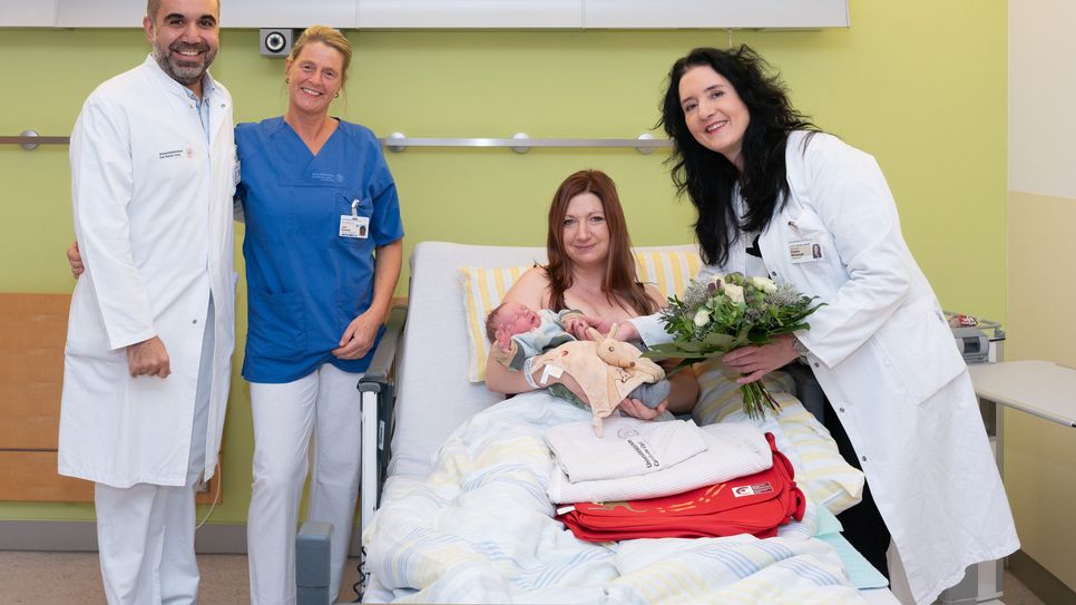 Prof. Cahit Birdir, leitender Oberarzt im Kreißsaal (l.), Schwester Jana (2.v.l.) und Prof. Pauline Wimberger, Direktorin der Klinik für Frauenheilkunde und Geburtshilfe, gratulieren Mama Isabell.