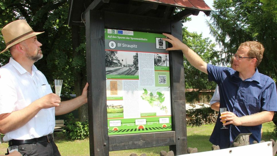 Der Burger Amtsdirektor Tobias Hentschel (li.) und Philipp Seemann (re.) von der Interessengemeinschaft (IG) Spreewaldbahn an der Schautafel, die auf dem Vereinsgelände der IG in Straupitz steht. Foto: sts