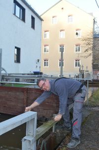 Der Müllermeister öffnet das Wehr. Der Wasserstand wird am Wehr reguliert.