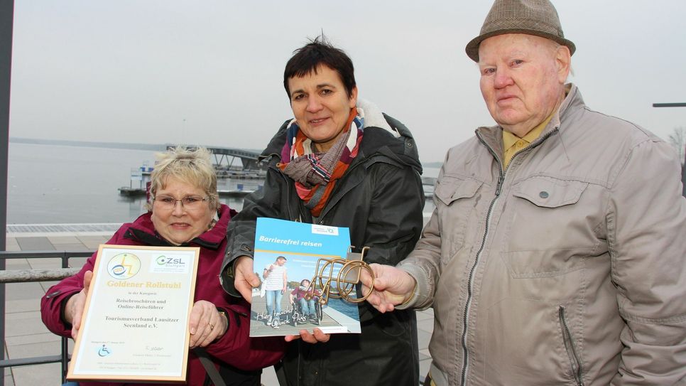 Den »Goldenen Rollstuhl« gab es für die Broschüre »Lausitzer Seenland - Barrierefrei reisen« des Tourismusverbandes Lausitzer Seenland e.V.. Kathrin Winkler (Mitte), Geschäftsführerin Tourismusverband Lausitzer Seenland e.V., Manfred Müller (re.), Blinden- und Sehbehinderten Verband Brandenburg e.V. Bezirksgruppe Senftenberg, und Marei Tuppatsch (li.), Mitglied der Arbeitsgruppe Barrierefrei des Tourismusverbandes Lausitzer Seenland e.V. und Urlaubstesterin für die Broschüre, präsentieren Broschüre, Urkunde und den Goldenen Rollstuhl. Foto: sts